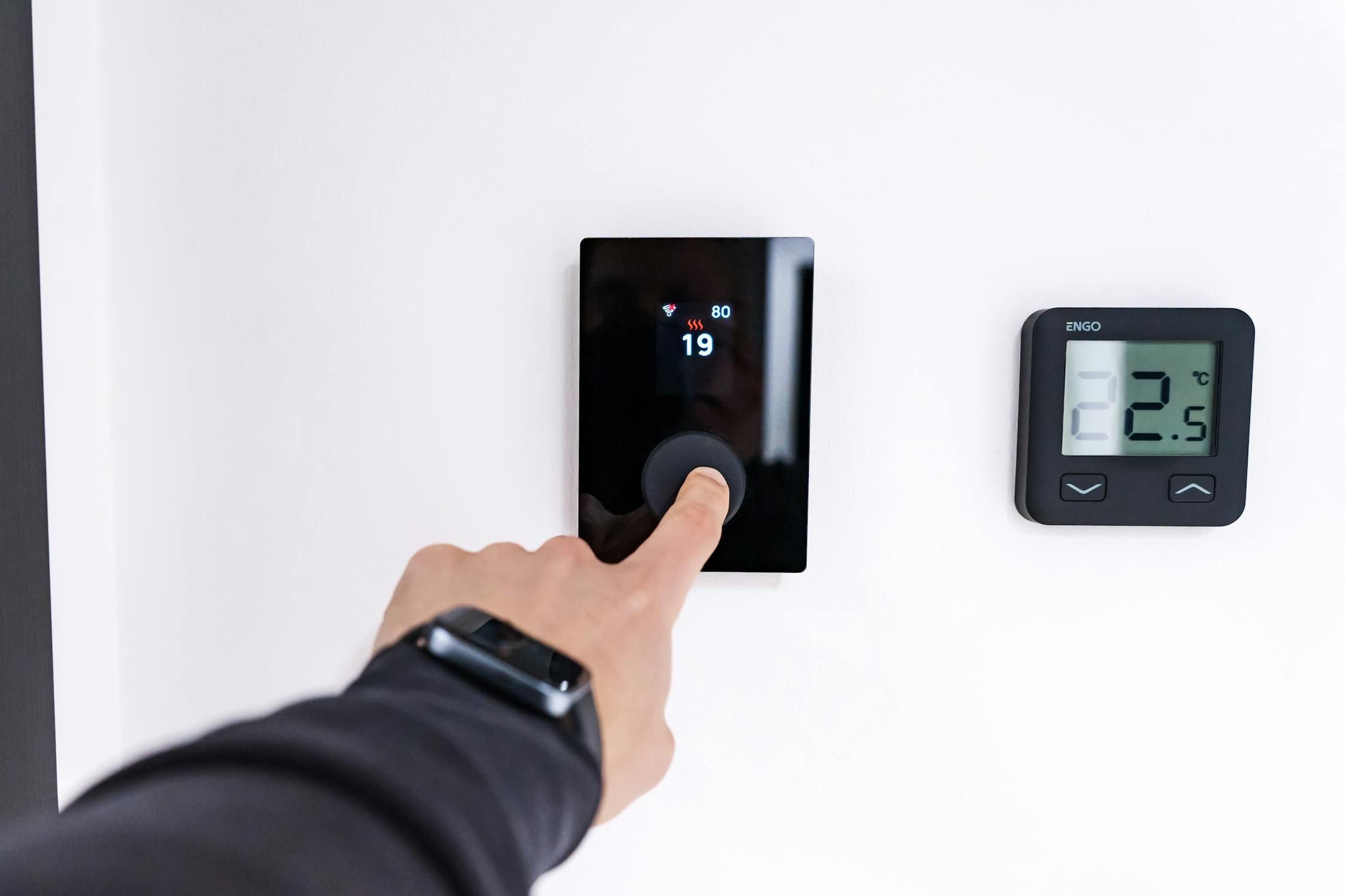 Hand adjusting a modern smart thermostat